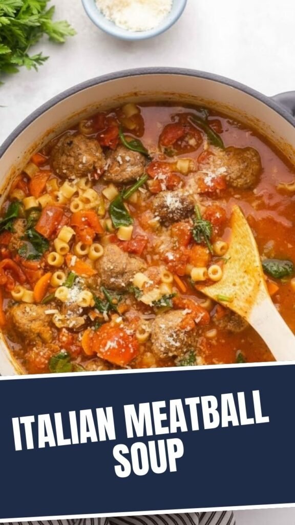 A steaming bowl of traditional Italian meatball soup with vegetables.