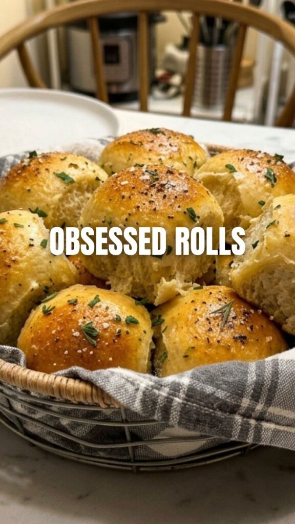 A basket of golden brown dinner rolls, freshly baked and warm.