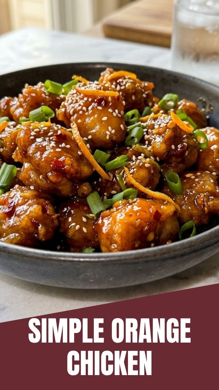 A serving of savory orange chicken garnished with green onions and sesame seeds.